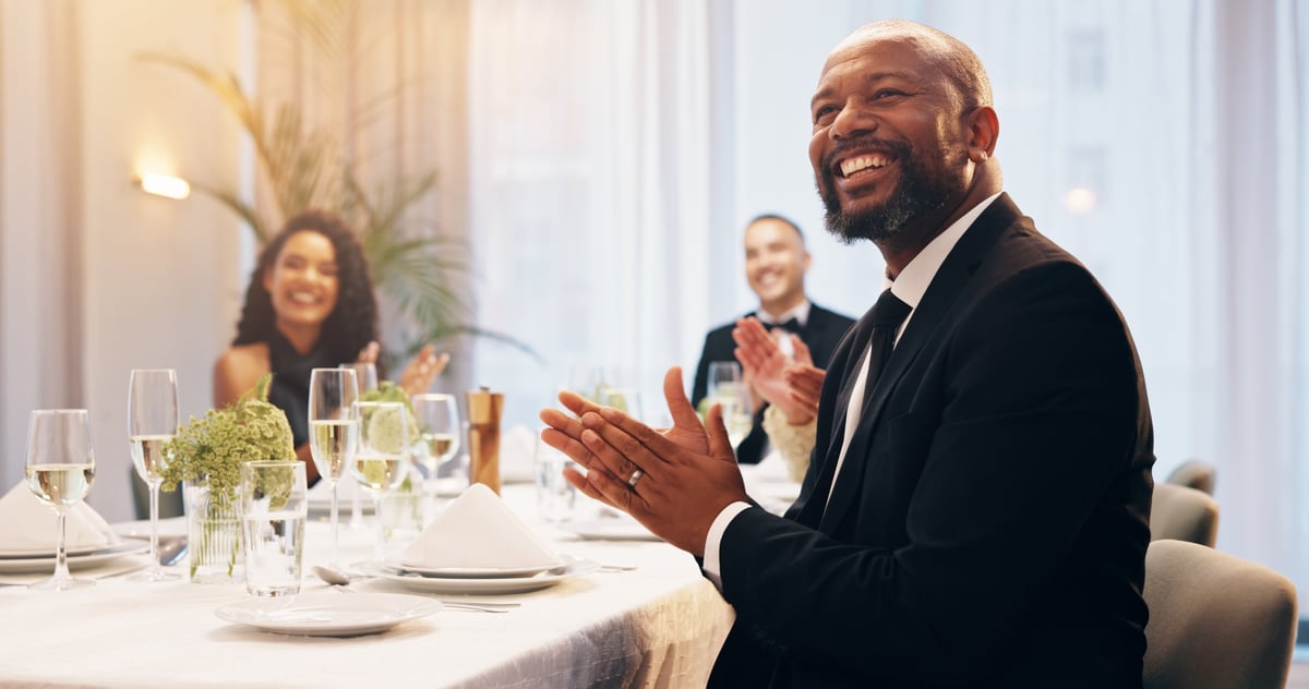 Guests in business attire raising champagne glasses in a toast at a corporate gala