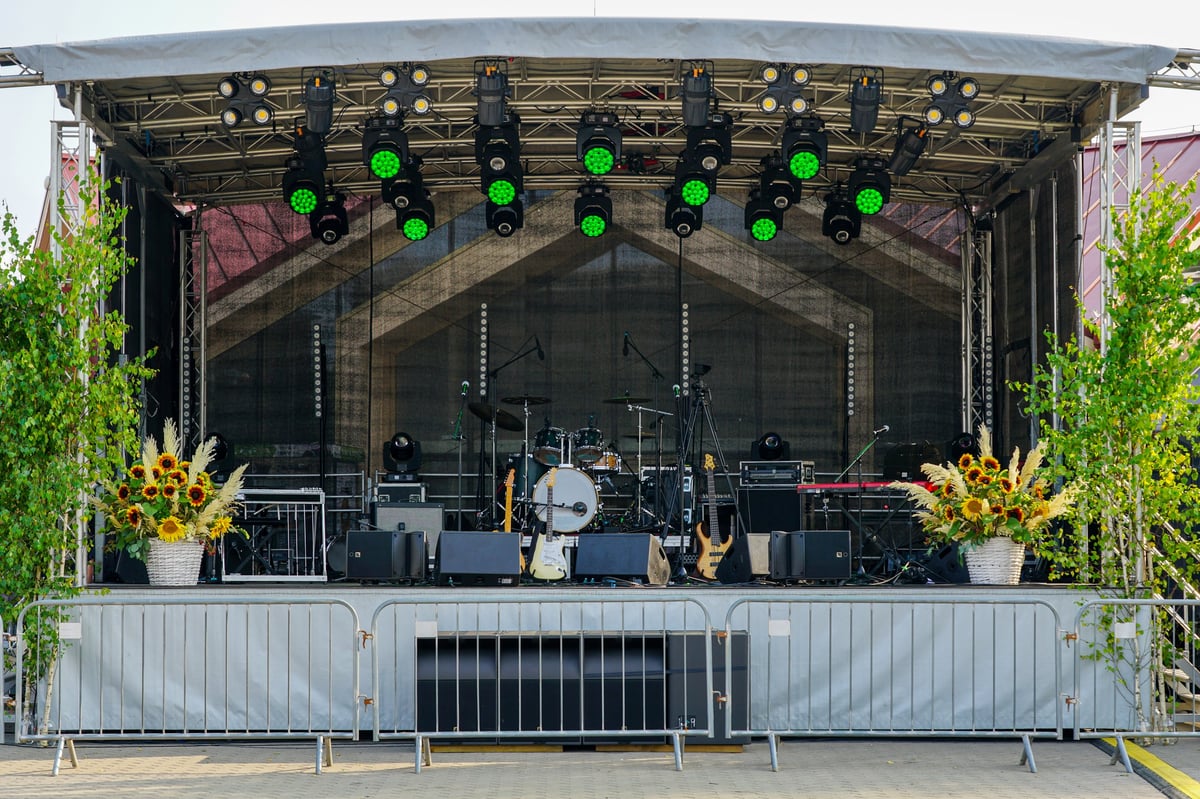 Outdoor festival stage with drums, guitars, speakers, and lighting set up before the event
