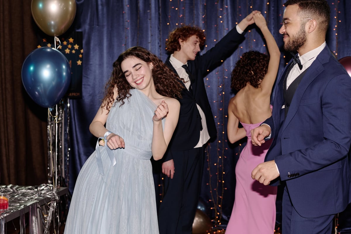 Teenagers in formal attire dancing together at a festive party celebration